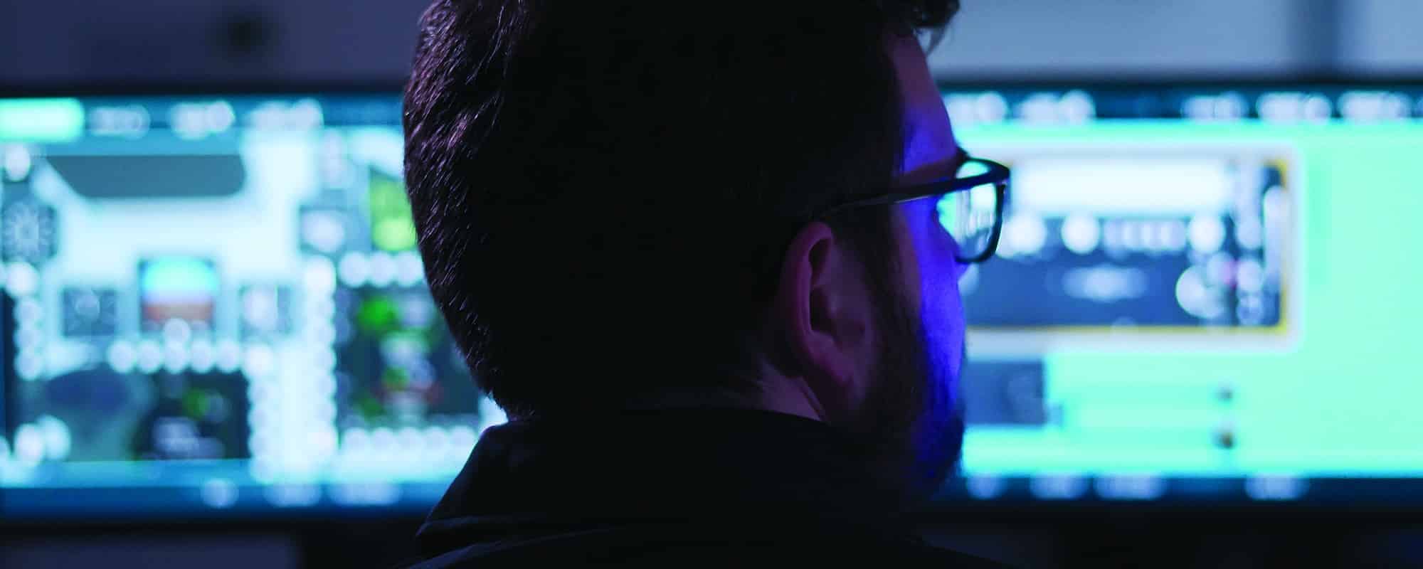 computer operator looking at multiple screens